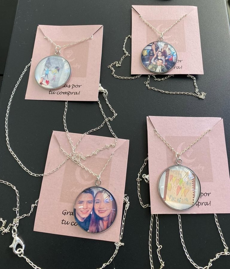 Cuatro collares con fotos distintas, presentados en sus tarjetas rosas sobre una mesa oscura.
